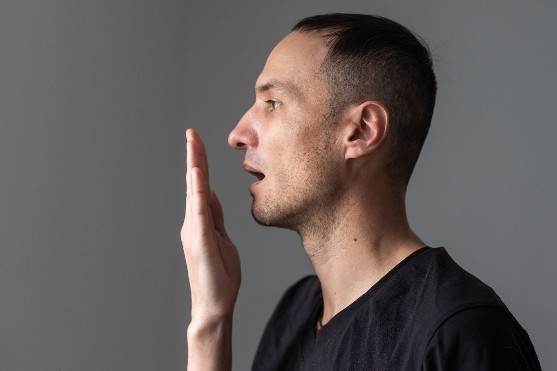 Close Up Of A Good-looking Man Putting His Hand In Front Of His Mouth And Checking His Bad Breath
