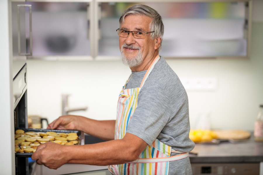 Senior man prepares healthy version of potatoes in the oven