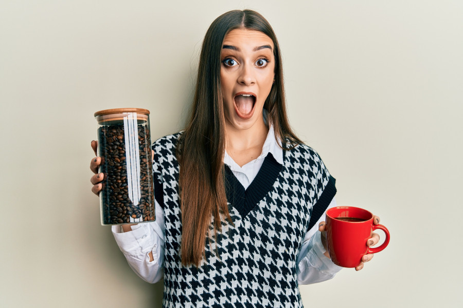 woman holding jar with coffee beans and drinking coffee