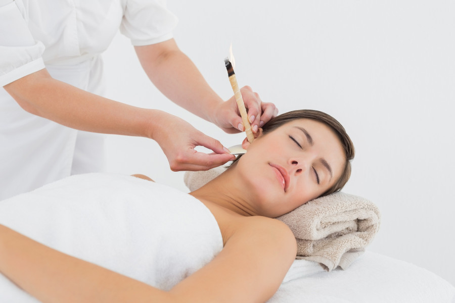 woman receiving ear candle treatment at spa center