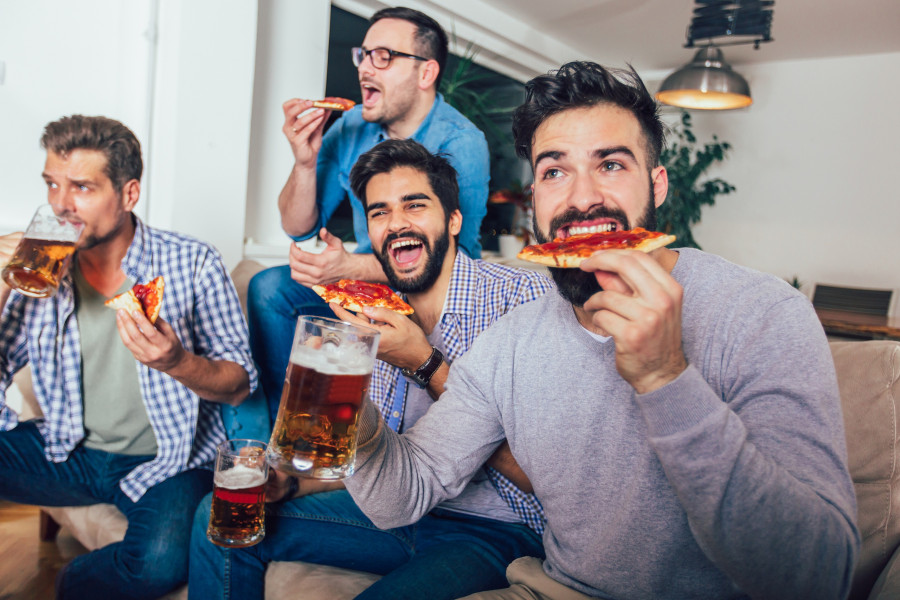 Friends Drinking Beer And Eating Pizza At Home