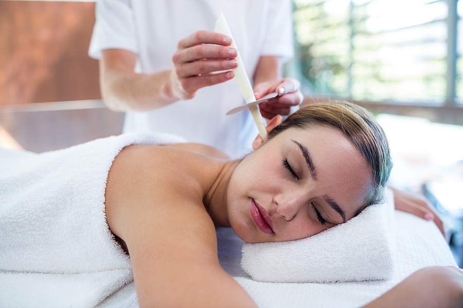 Woman receiving ear candle treatment at spa