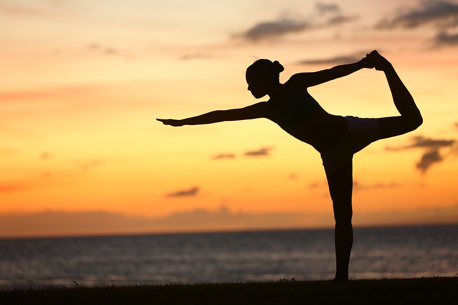 Yoga woman in sunset at beach doing king dancer pose