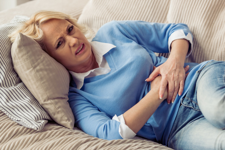 woman is having stomach ache while on couch