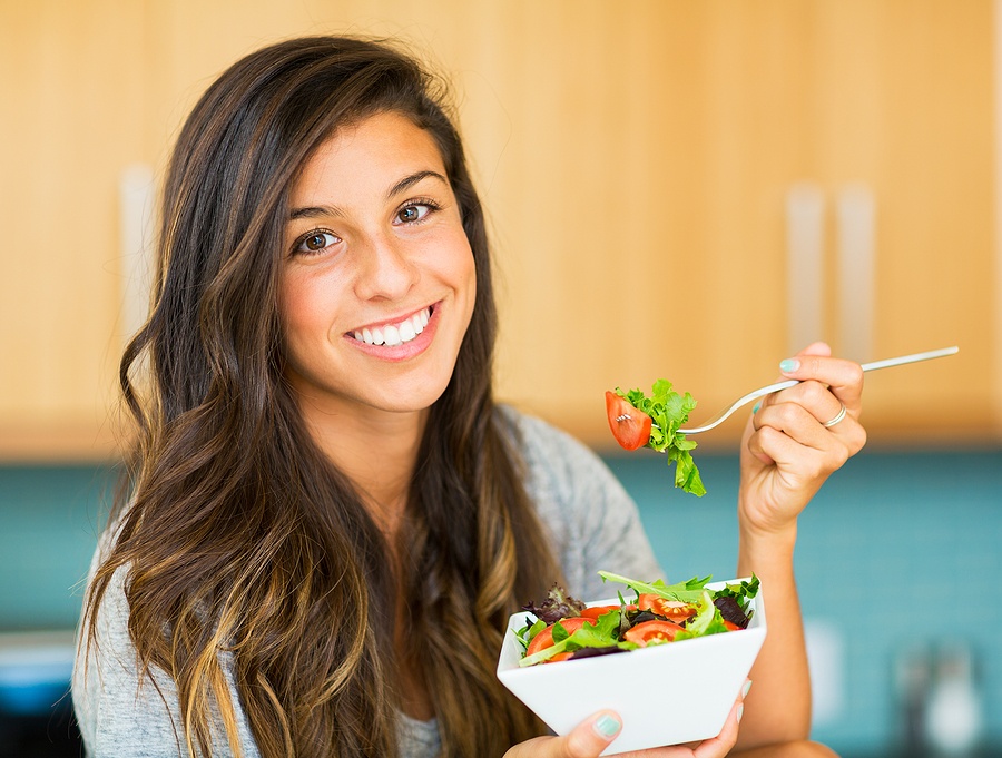 woman eating a bowl of healthy organic salad