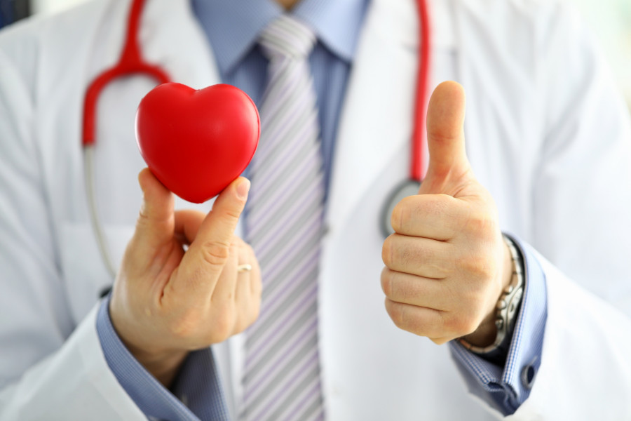 doctor holds red toy heart and show OK or approval sign