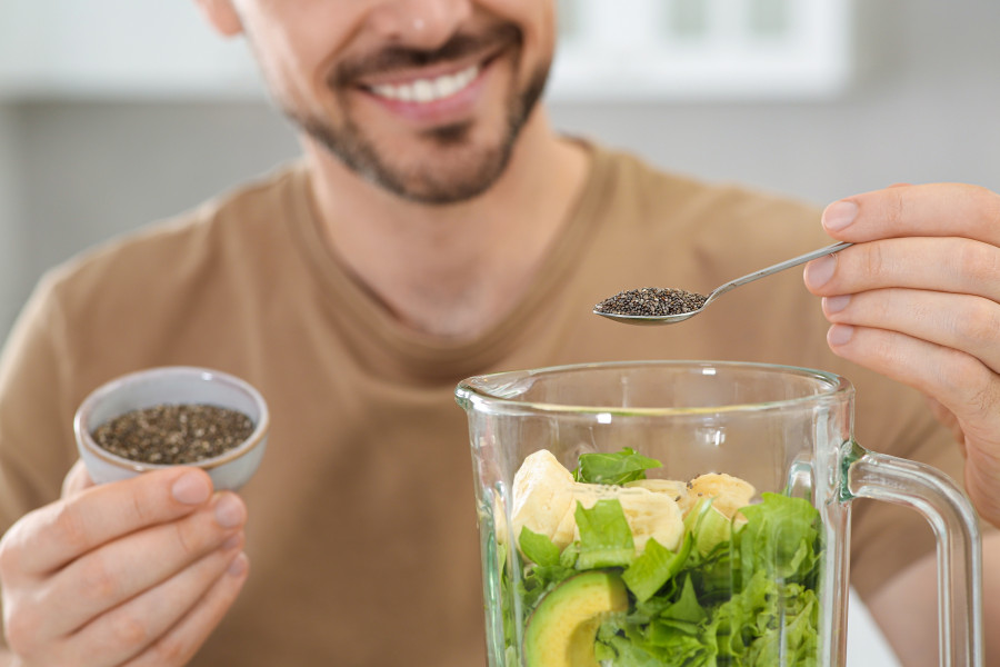Man Adding Chia Seeds Into Blender With Ingredients For Smoothie