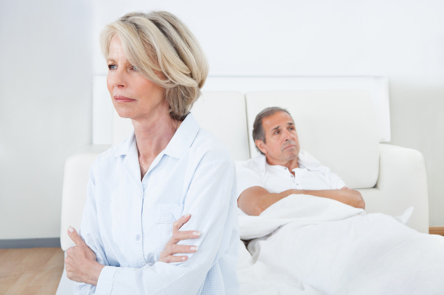 Sad Woman Sitting At The Edge Of Bed In Front Of Man