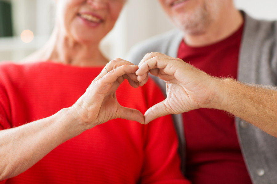 senior couple showing hand heart gesture