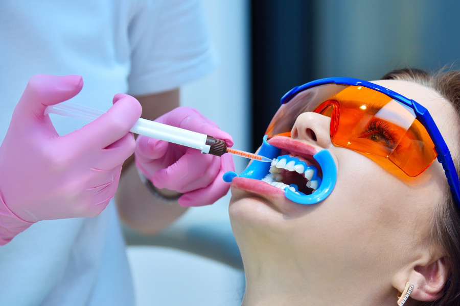 Woman Dentist Applies Gel To Teeth Before Teeth Whitening Procedure