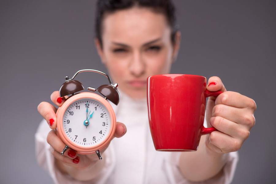 woman holding coffee cup and an alarm clock