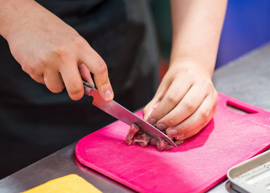 Cutting Raw Meat On Board In Kitchen