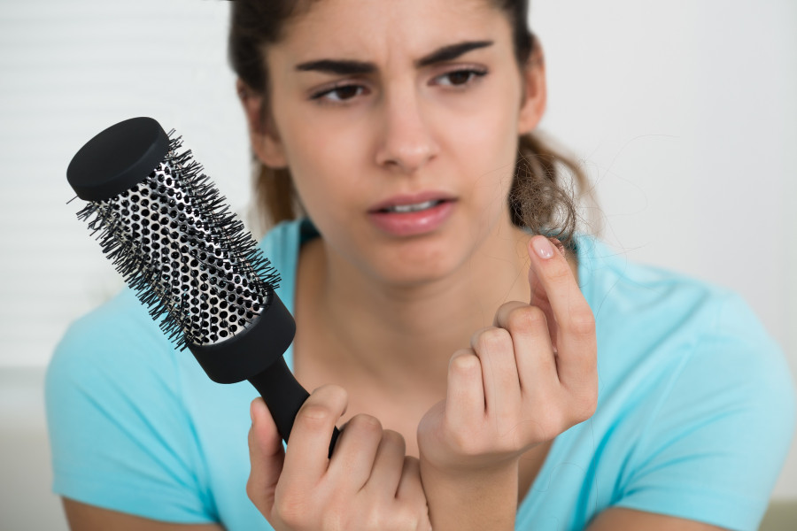 Woman Holding Comb While Looking At Hair Loss