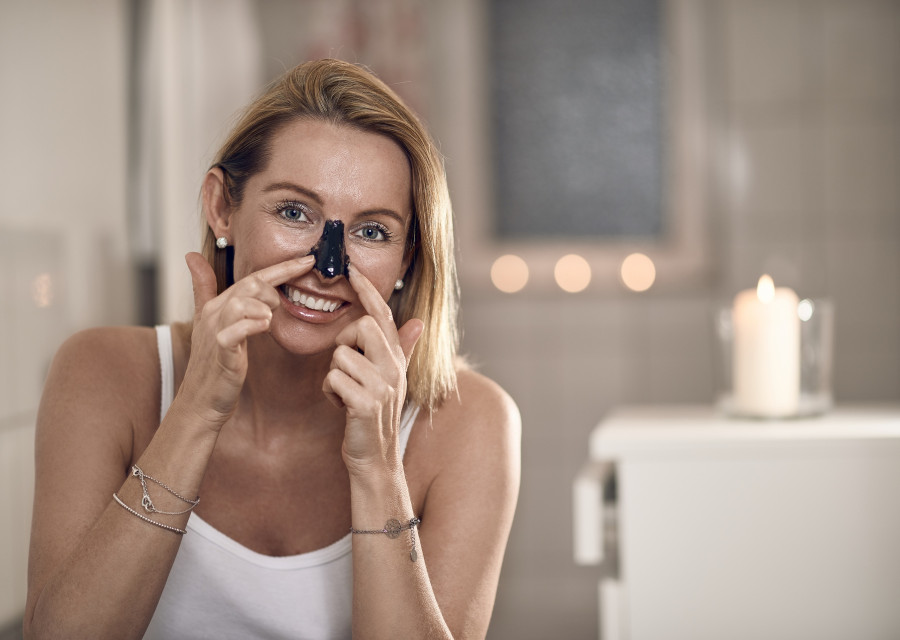 woman applying an anti-aging face mask to her nose