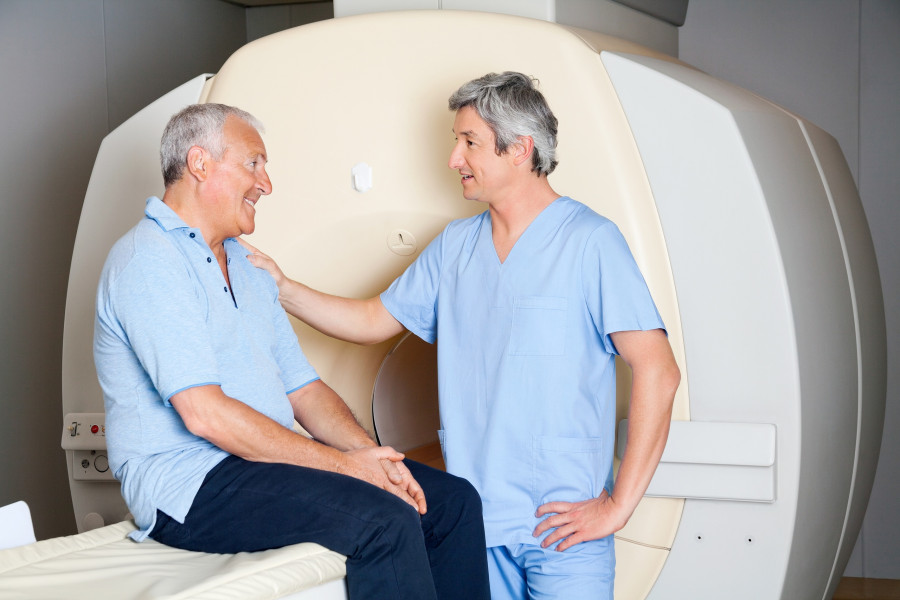 Man radiologic technician comforting senior patient MRI scan