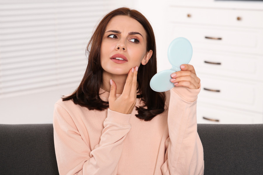 Woman Looking In Mirror And Touching Her Face