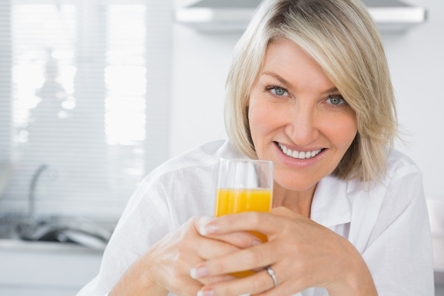 woman having orange juice in kitchen