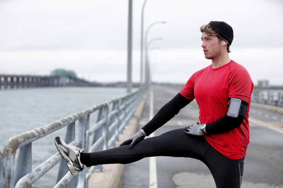 fitness man runner stretching legs doing running warmup
