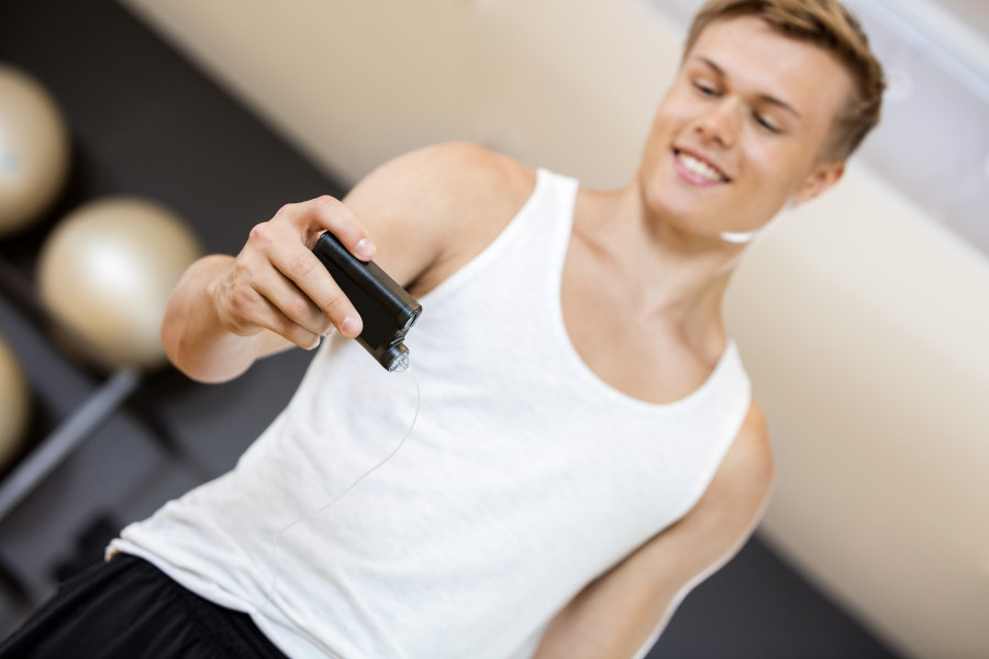 Young Man Holding Glucose Monitor In Gym