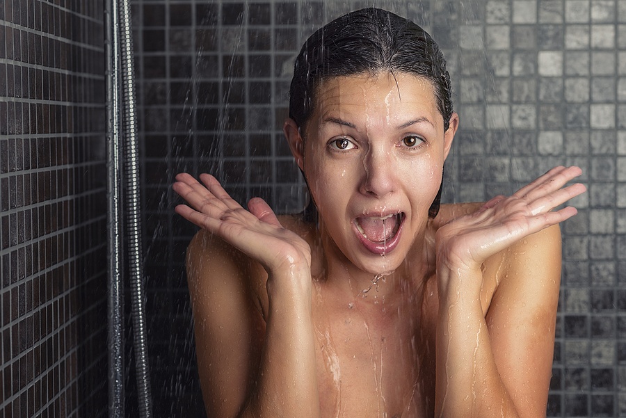 Young Woman Reacting In Shock To Hot Shower Water
