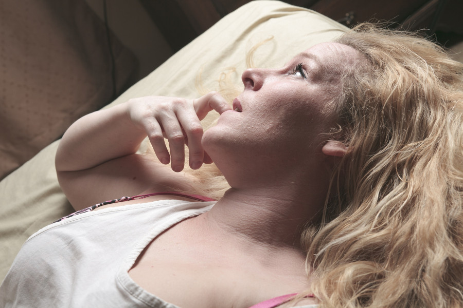 A woman feel sick lying down on bed