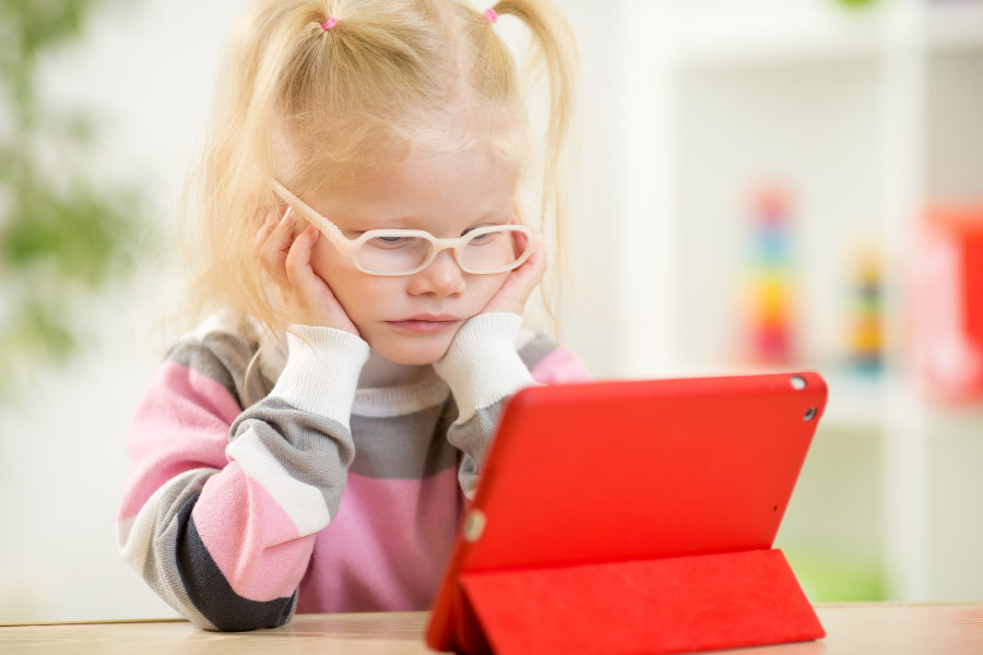 child in glasses looking at mini tablet pc screen
