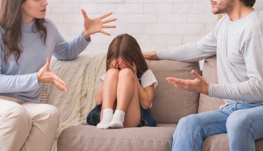 Innocent Little Girl Sitting Between Arguing Parents And Crying