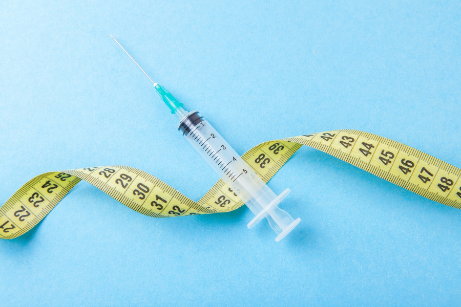 Syringe With A Needle And Yellow Measuring Tape