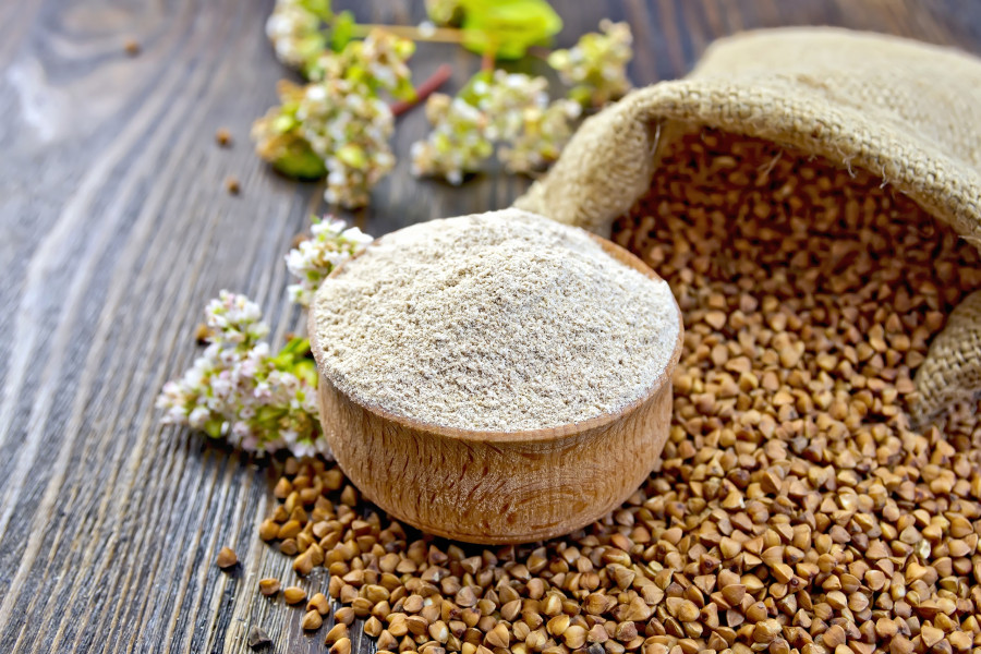 Flour buckwheat in bowl with cereals and flower on board