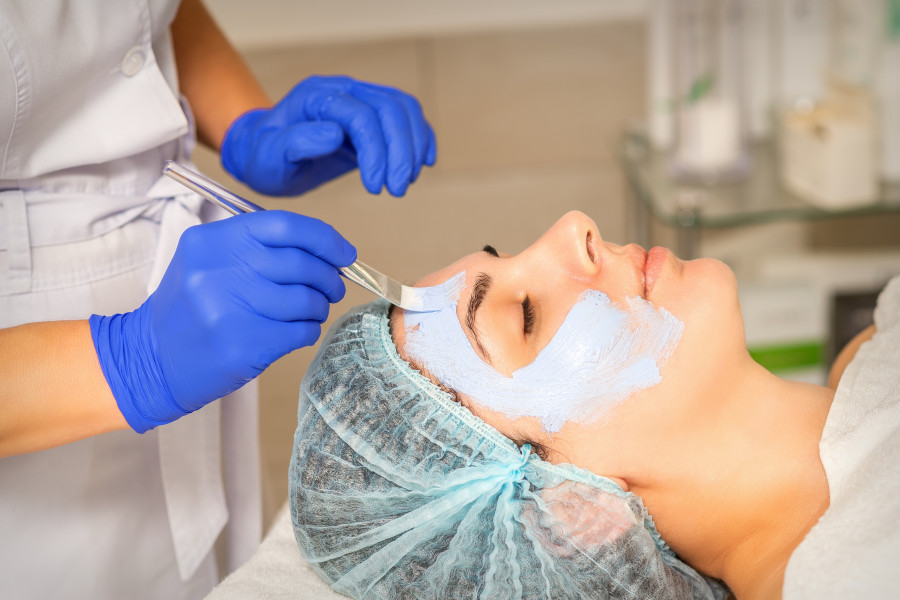 Beautician With Brush Applies A Photochemical And Glycolic peeling face mask