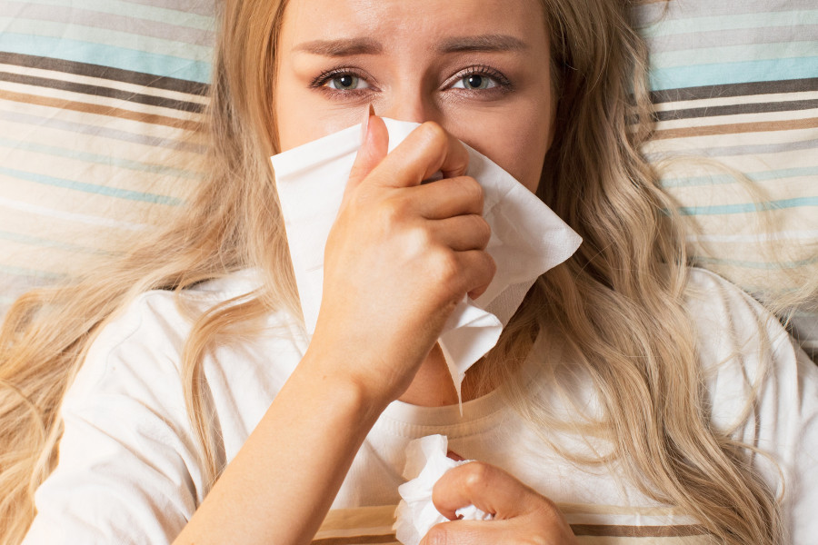 woman with paper napkin blowing nose