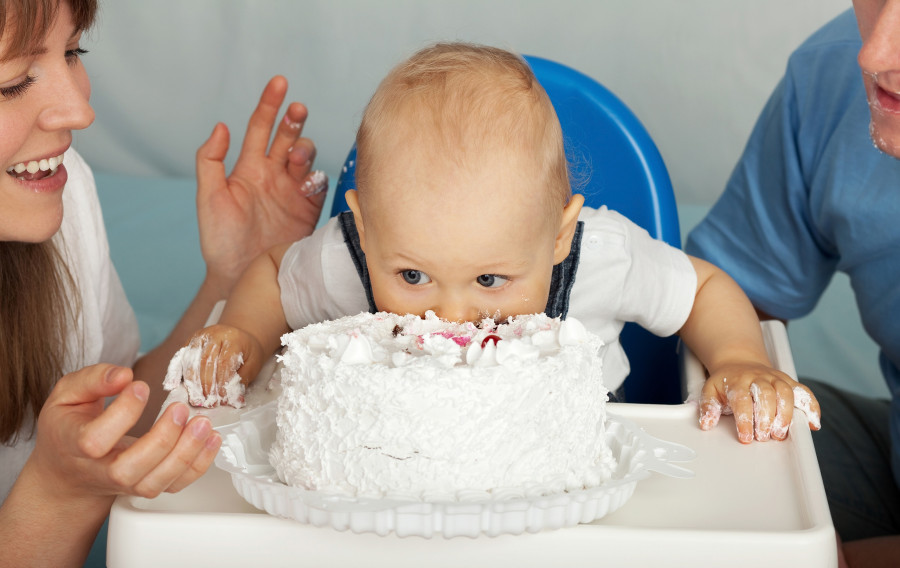 Kid eats cake. Family celebrates the first birthday of son.