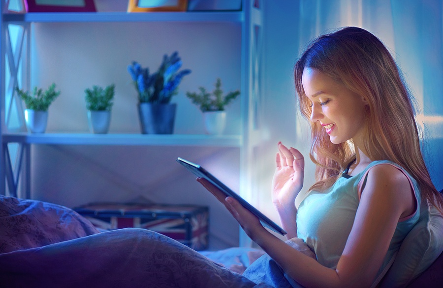 Woman using tablet pc in her bed at night