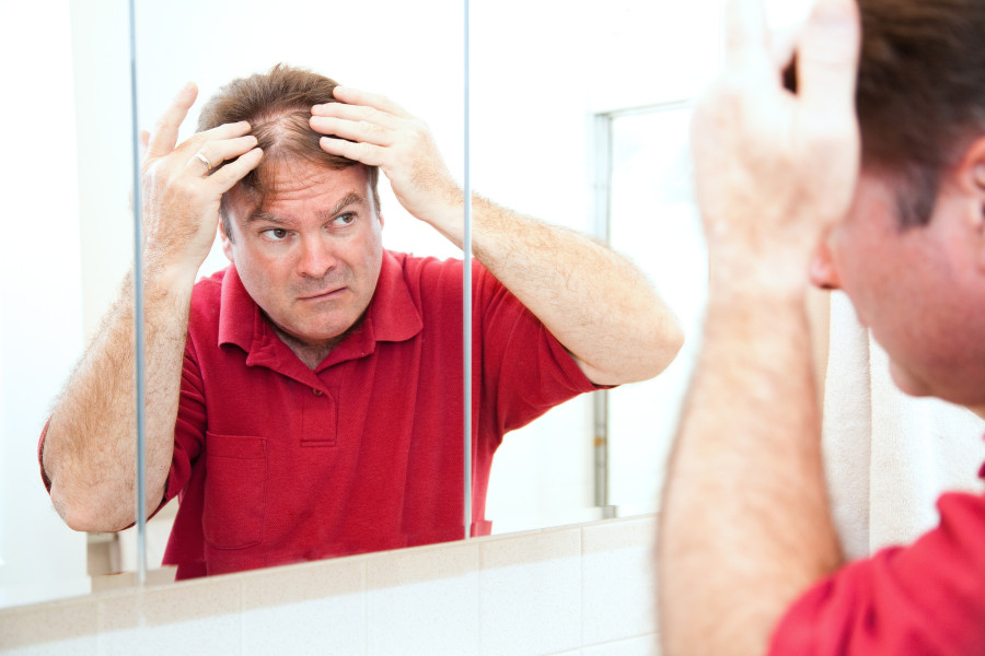 Man checking for thinning hair in the mirror