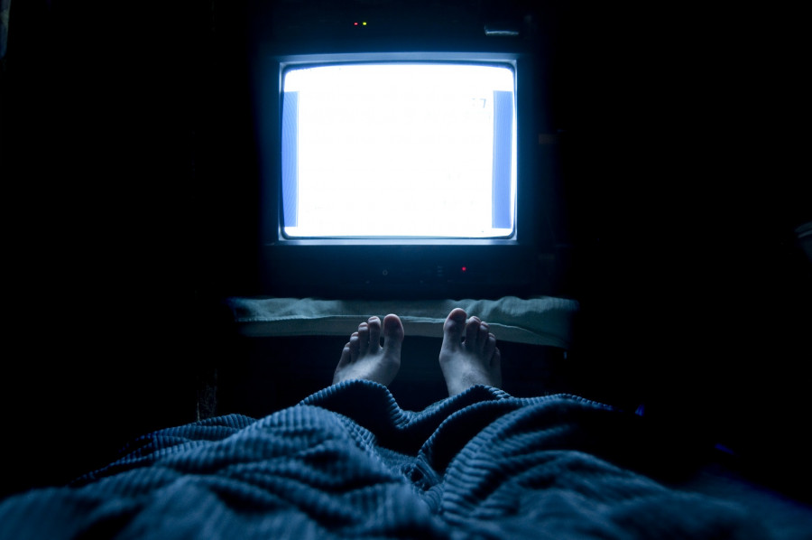 Person watches TV at night in his bed