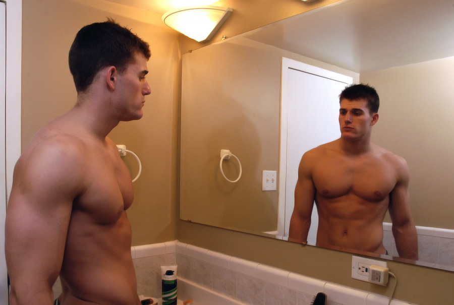 a man checks himself out in the bathroom mirror