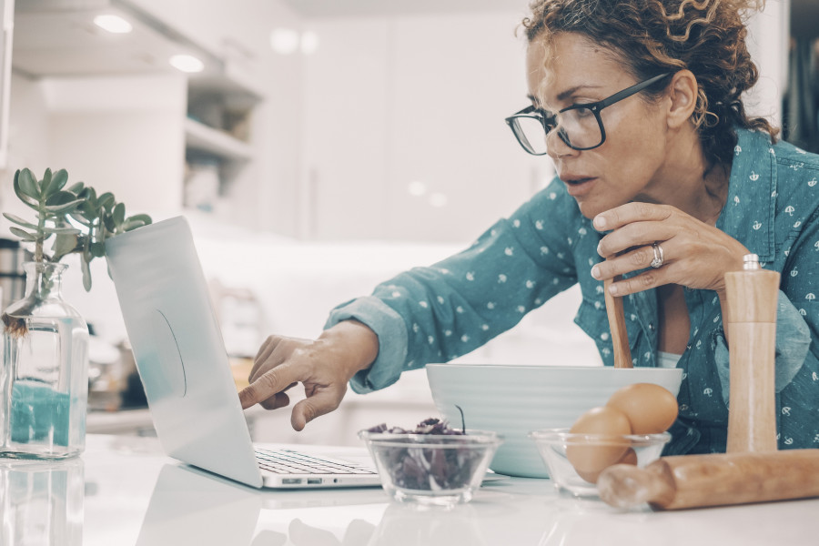 Woman Cooking A Cake At Home Using Laptop For Recipy