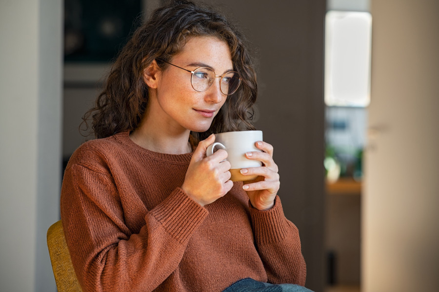 Pensive woman drinking hot coffee at home. Thoughtful
