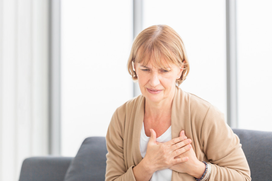 Senior Woman With Pain On Heart In Living Room