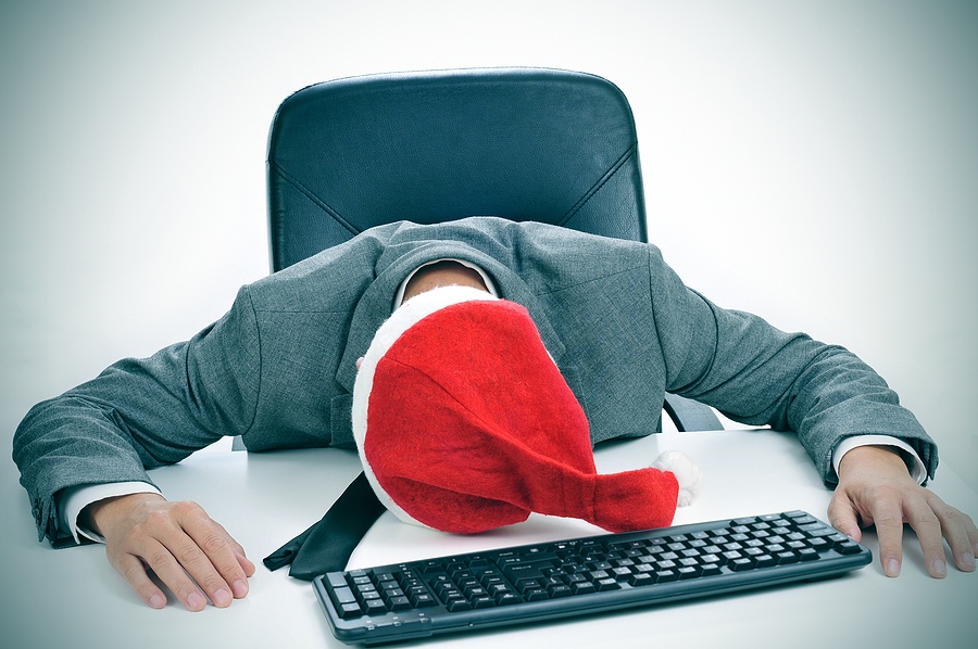 a man in suit with a santa hat sleeping in his desk after an off