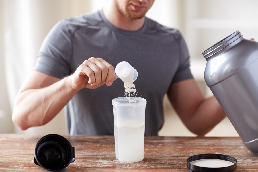 man with jar and bottle preparing protein shake