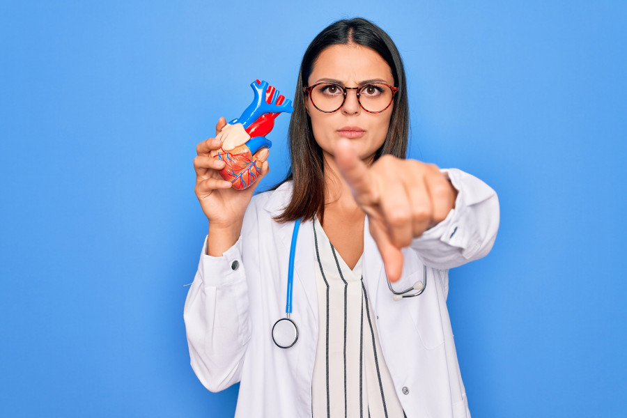 cardiologist wearing stethoscope holding heart model