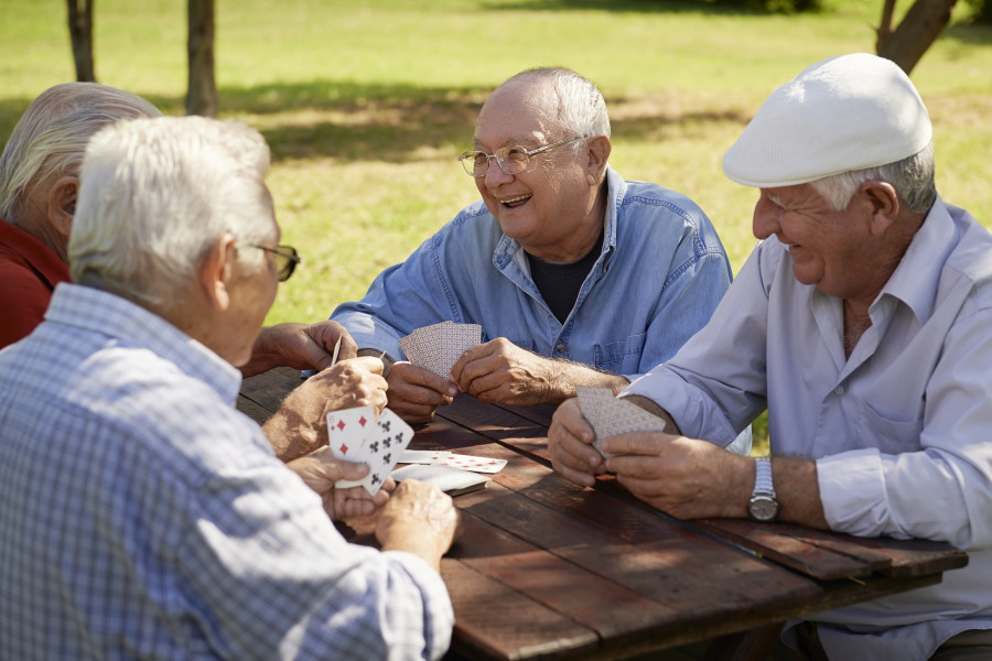 elderly men playing cards game at park