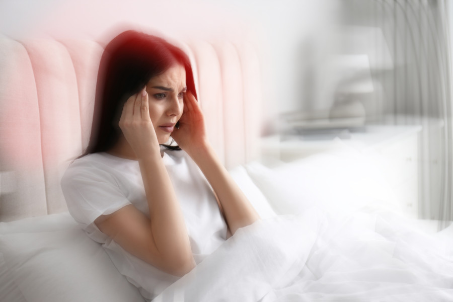 Young Woman Suffering From Migraine In Bed At Home