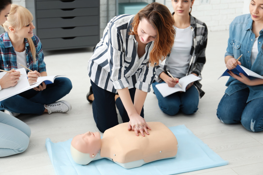 Group of people practicing CPR on mannequin at first aid class