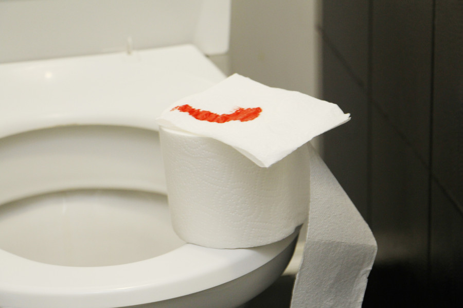 A Roll Of Toilet Paper With Blood Lies On The Toilet
