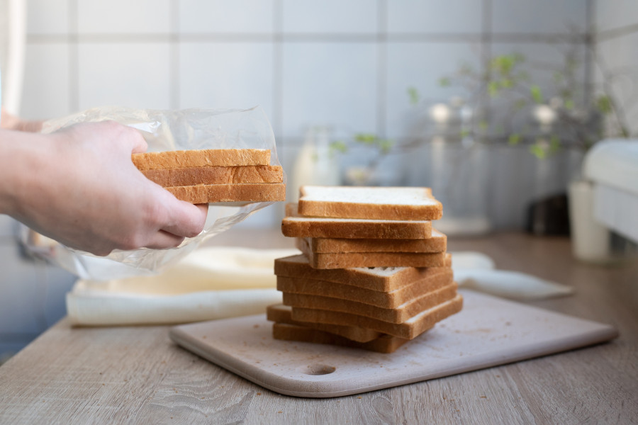 Female Hands Taking Out Slices Of Bread From A Package