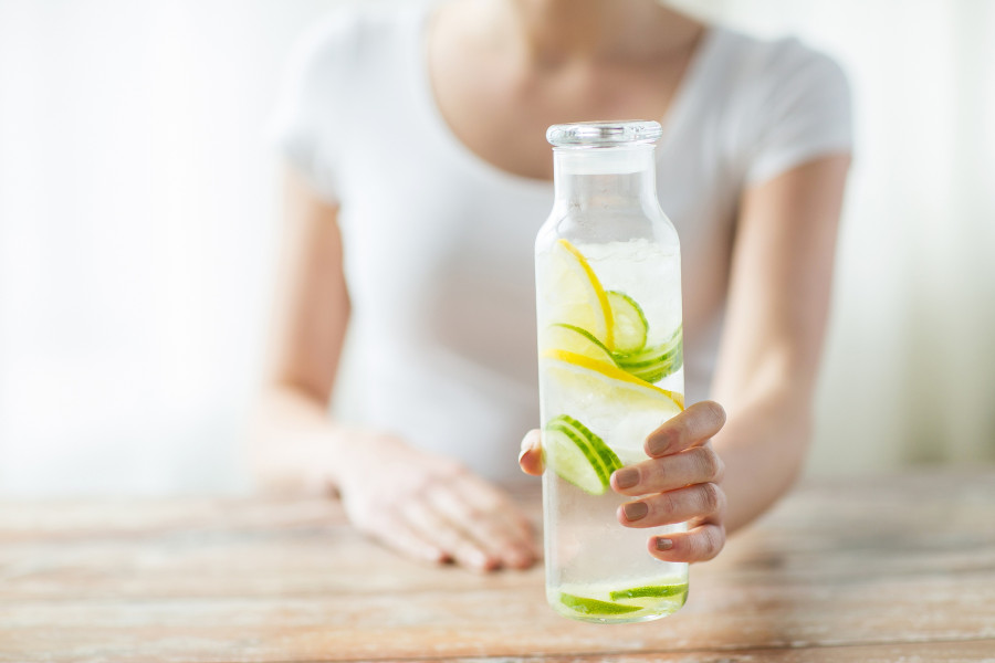 woman with fruit water in glass bottle