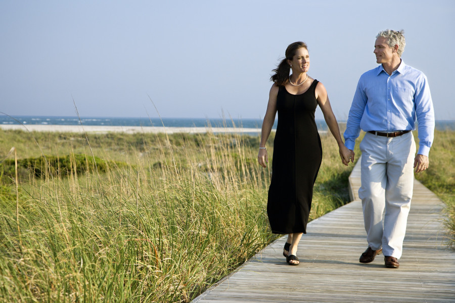 couple holding hands and walking on walkway